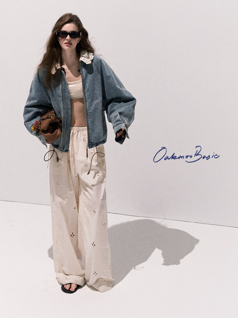 Model wearing a denim jacket with cream wide-leg pants and sunglasses