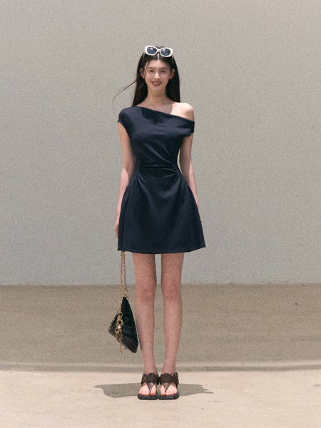 Model wearing a dark off-shoulder mini dress with a small chain-strap bag and sandals