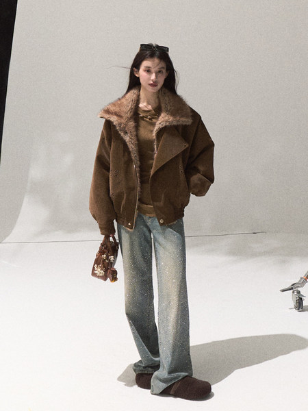 Model wearing a brown oversized jacket with wide-leg jeans and a small handbag