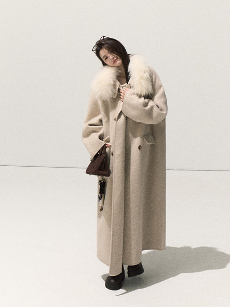 Model wearing a long beige coat with a fur collar