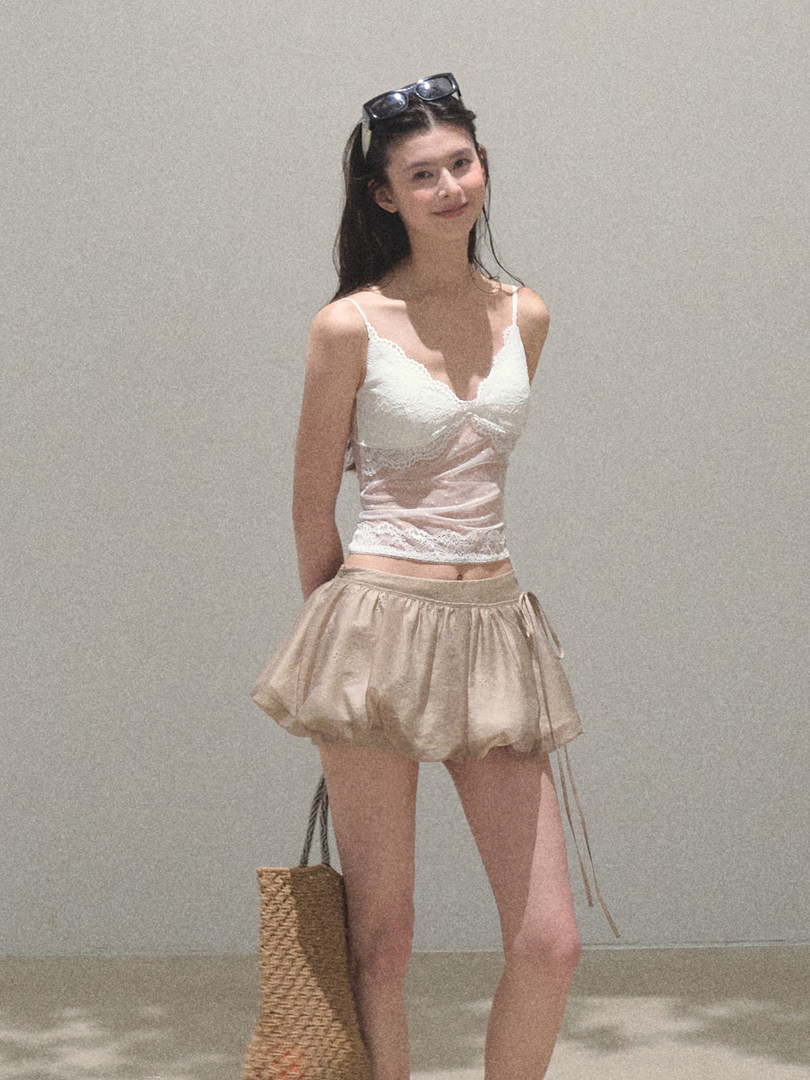 Woman modeling a white lace camisole and beige bubble skirt
