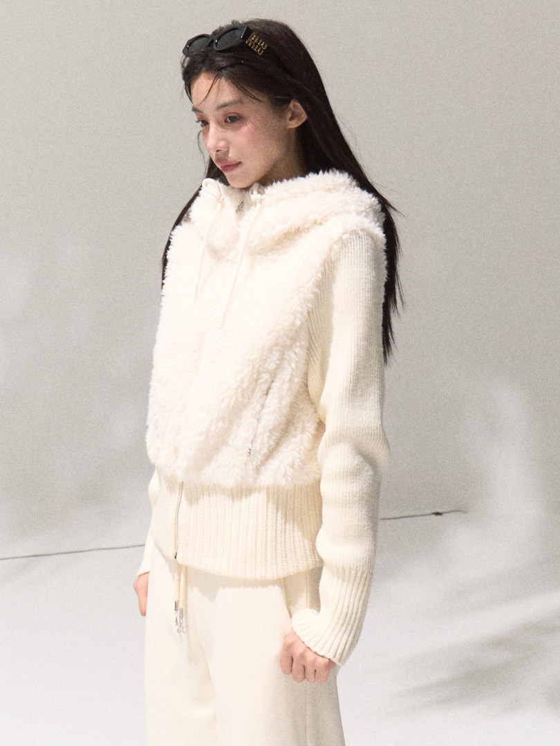 Woman wearing a cream fuzzy hooded vest with knit long sleeves