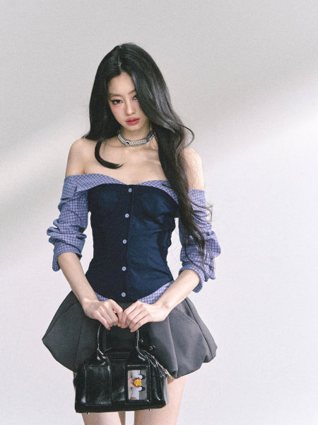 Woman modeling an off-shoulder corset-style top with a black skirt and handbag