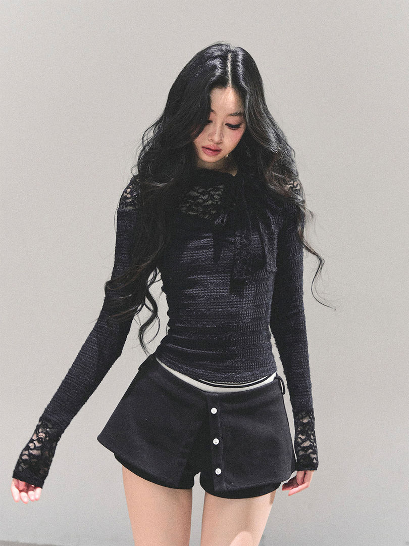 Model wearing a black long-sleeve lace top with black buttoned shorts