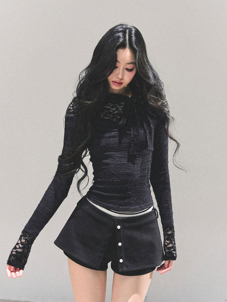 Model wearing a black long-sleeve lace top with black buttoned shorts