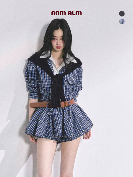 Model wearing a blue plaid coordinated outfit with belt and layered shirt styling