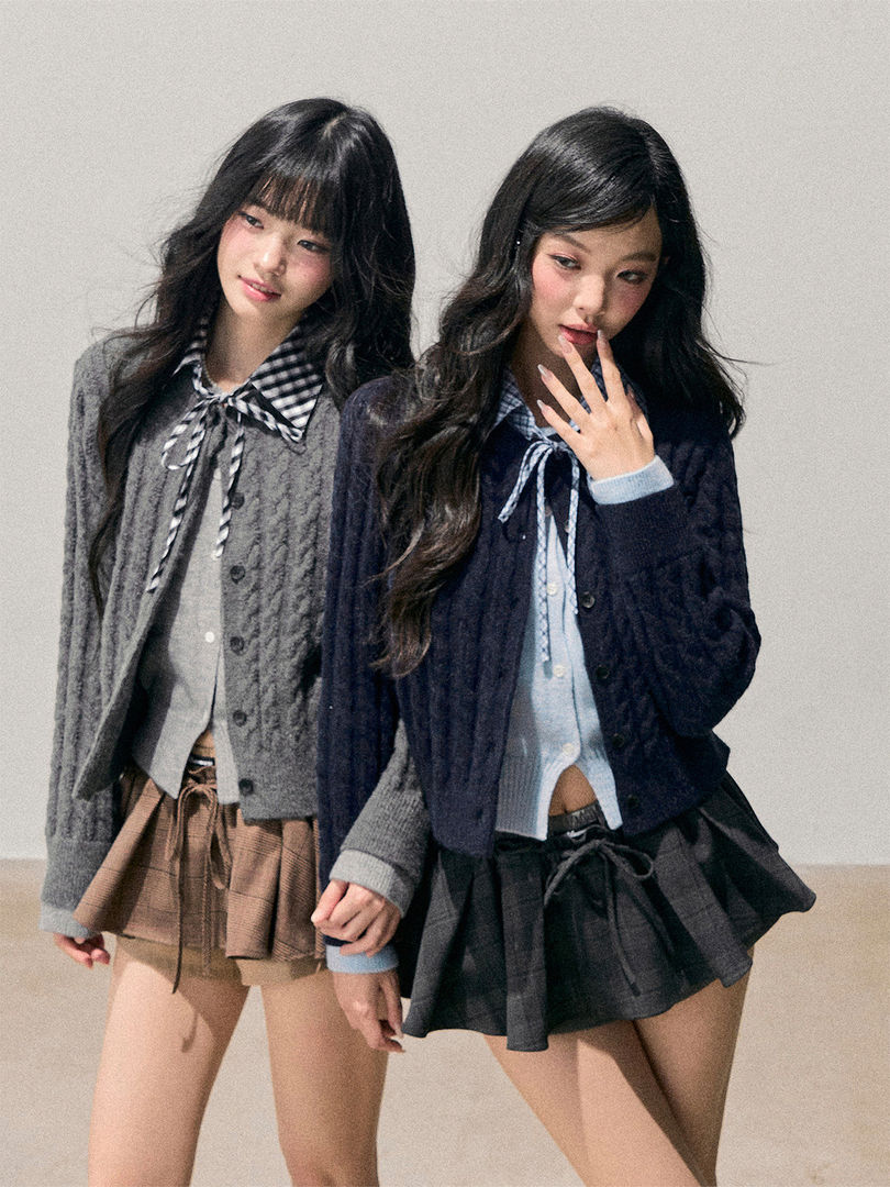 Two models wearing layered knit cardigans with ribbon ties and plaid skirts