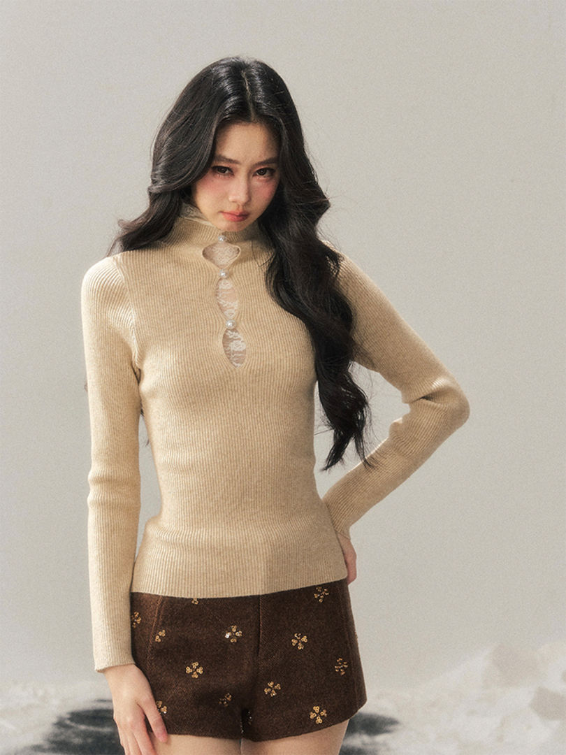 Model wearing a beige ribbed knit long-sleeve top with decorative front detail and brown patterned shorts