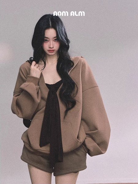 Model wearing an oversized brown hoodie set with black tie detail and matching shorts