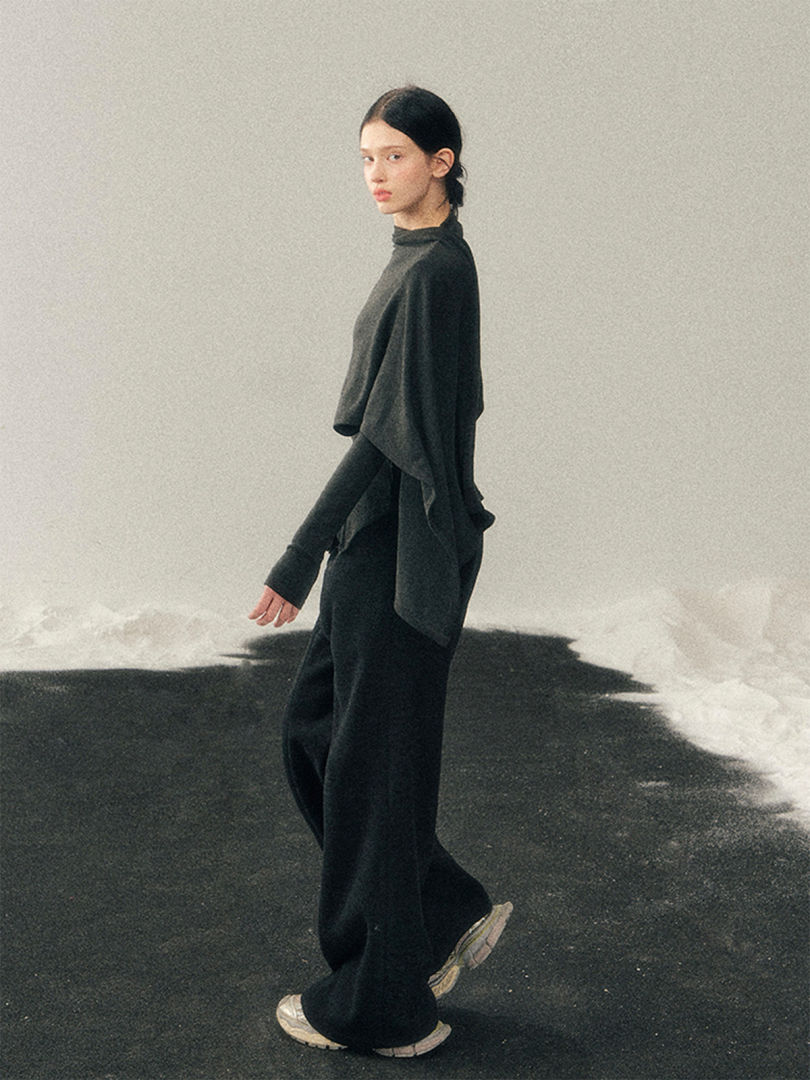 Model wearing a dark minimalist layered sweater and wide-leg pants with sneakers