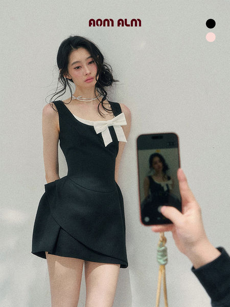 Black sleeveless mini dress with a white bow detail worn by a model