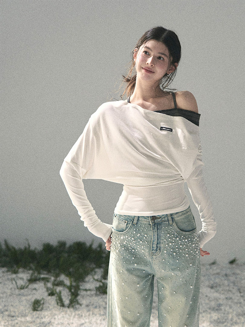 Woman wearing a white off-shoulder long-sleeve top and light wash embellished jeans