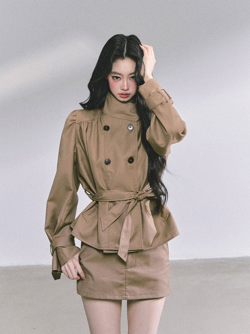 Model wearing a beige belted double-breasted jacket with matching mini skirt