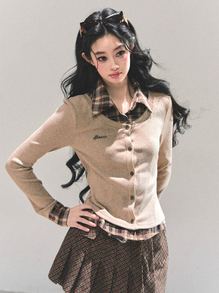 Woman modeling a beige knit cardigan layered over a plaid shirt with a matching plaid skirt