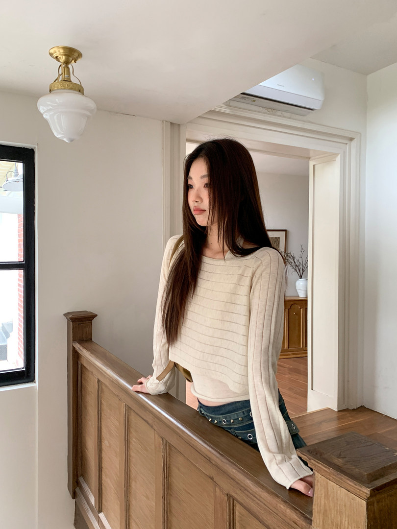 Woman wearing a cream ribbed long-sleeve knit top