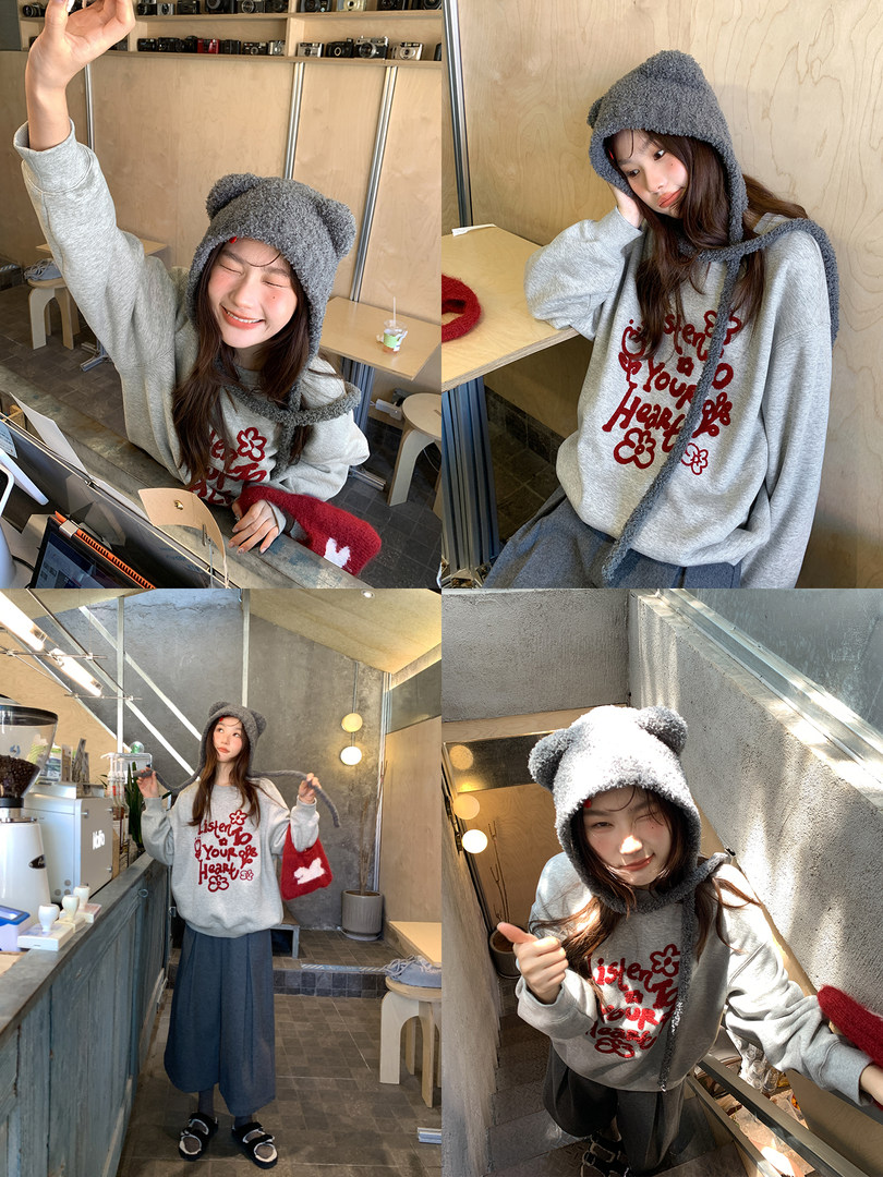 Model wearing a gray graphic sweatshirt and fuzzy hooded hat