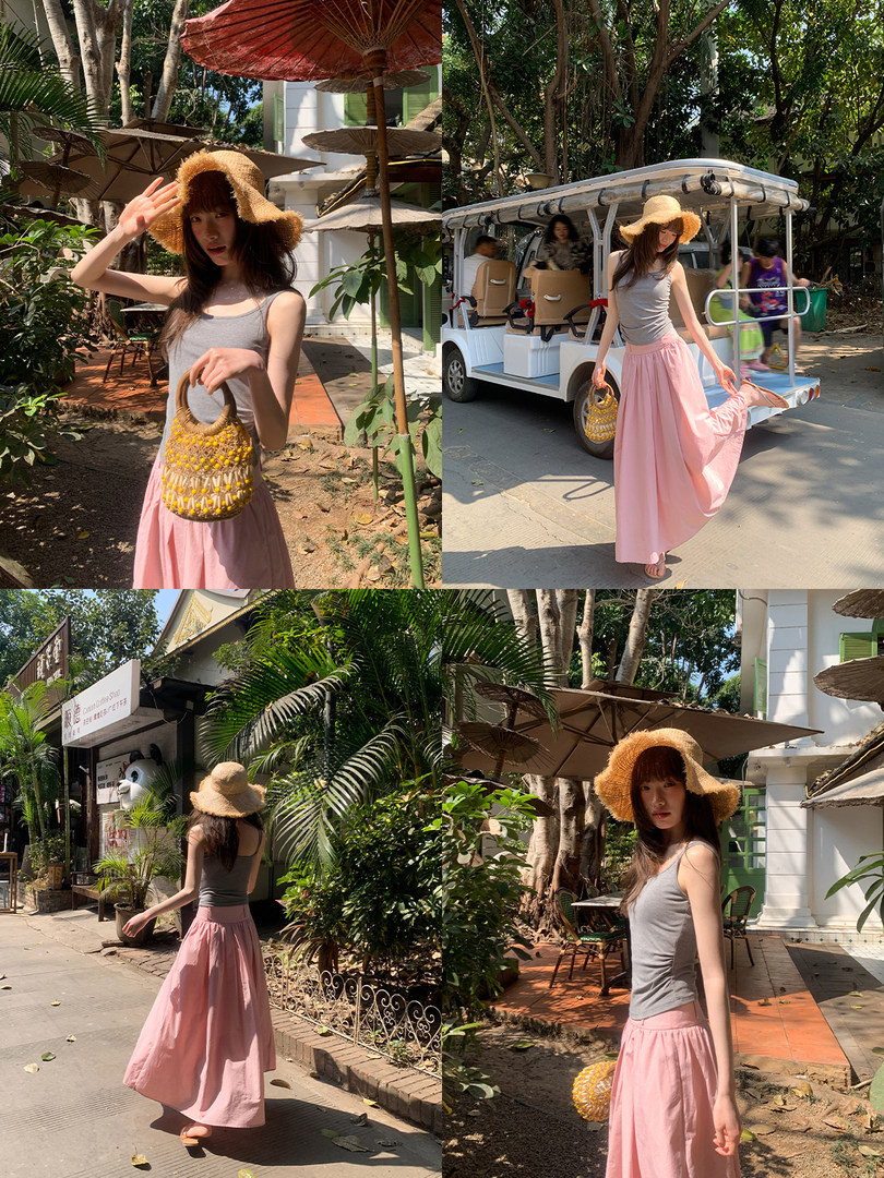 Woman wearing a gray tank top, pink skirt, sun hat, and woven bag in a tropical outdoor setting