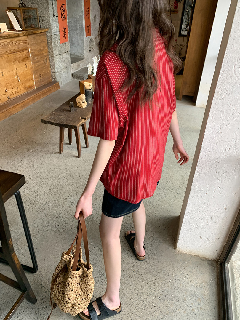 Woman wearing a red striped short-sleeve shirt with black skirt and woven bag