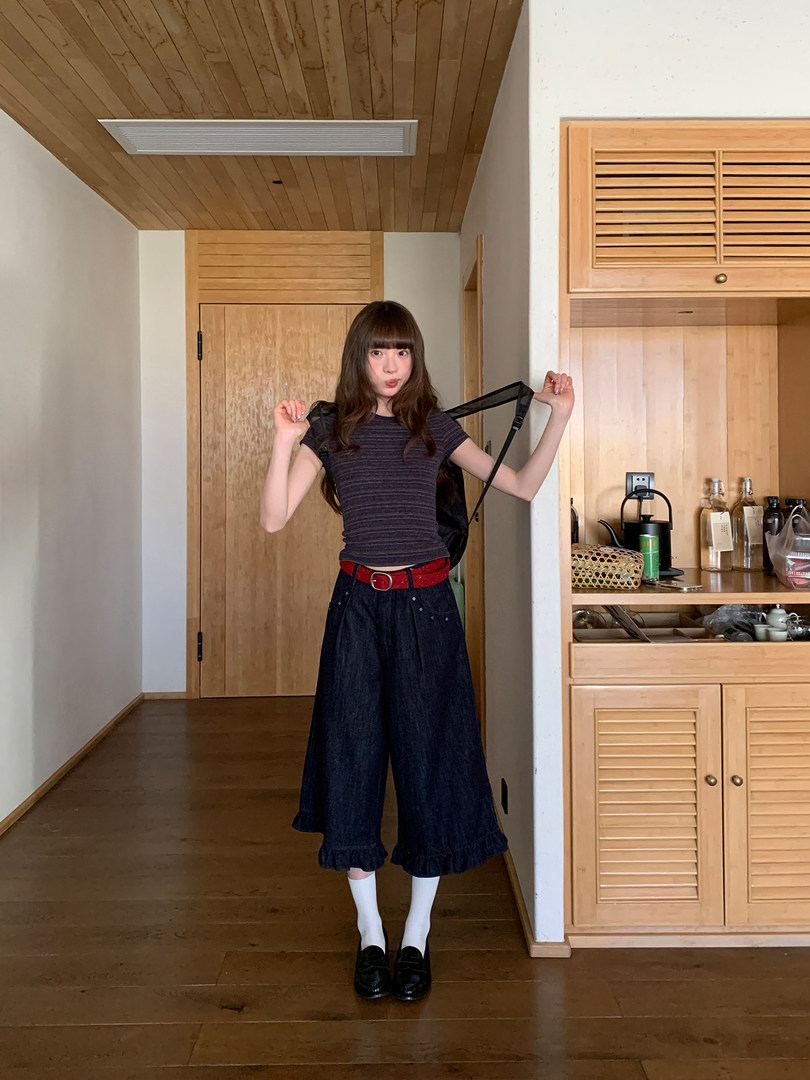 Woman wearing a striped fitted top with wide-leg dark pants, a red belt, and loafers
