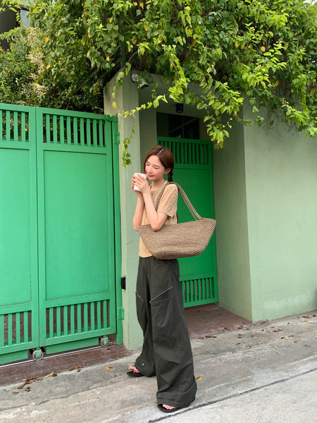 Woman wearing a woven tote bag with a casual summer outfit outdoors