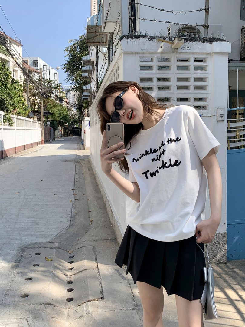 Woman wearing a white graphic T-shirt and black skirt outdoors