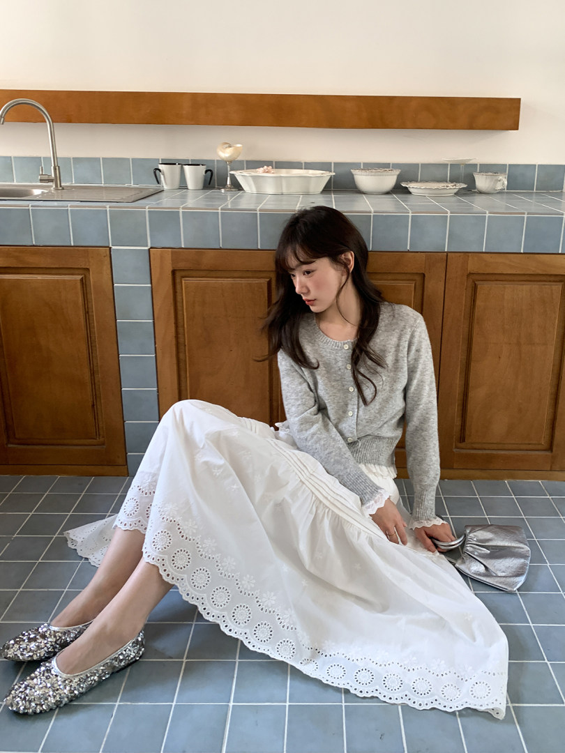 Woman wearing a gray cardigan with a white lace-trim skirt and glitter flats