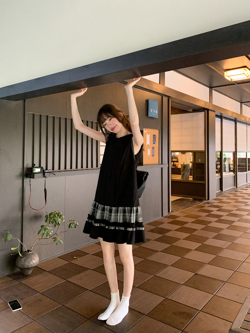 Black sleeveless dress with plaid ruffle hem worn by a model