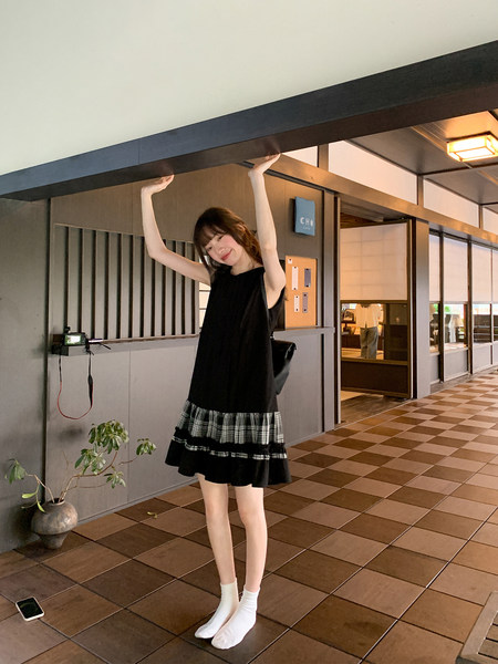 Black sleeveless dress with plaid ruffle hem worn by a model