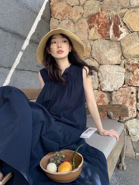 Woman wearing a navy sleeveless dress with a wide-brim hat