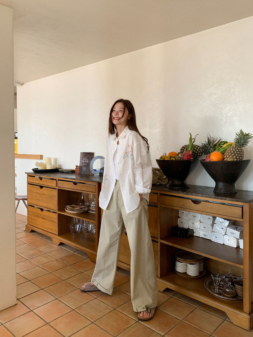 Model wearing a white oversized shirt with beige wide-leg pants