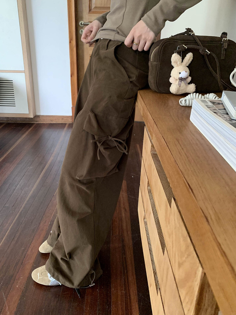 Person wearing brown wide-leg cargo pants indoors with a handbag on the table
