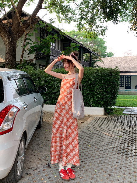 Woman wearing an orange plaid sleeveless dress outdoors