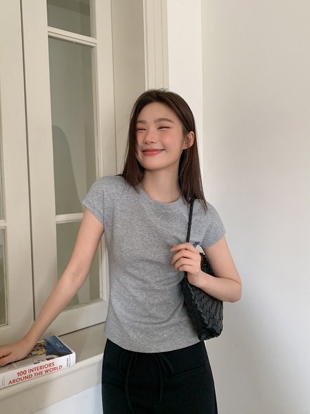 Woman wearing a gray short-sleeve T-shirt with a black woven shoulder bag