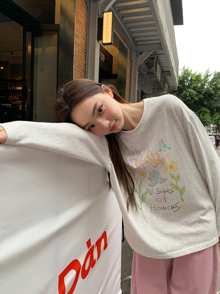 Model wearing a light gray floral graphic sweatshirt with pink pants