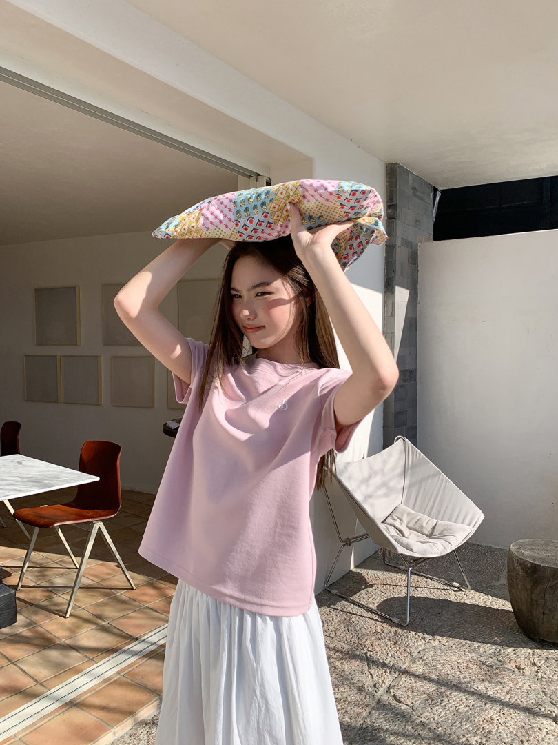 Woman wearing a light pink T-shirt and white skirt indoors