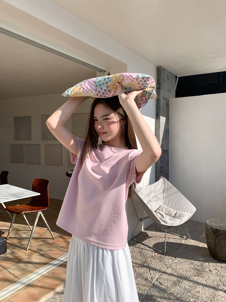 Woman wearing a light pink T-shirt and white skirt indoors