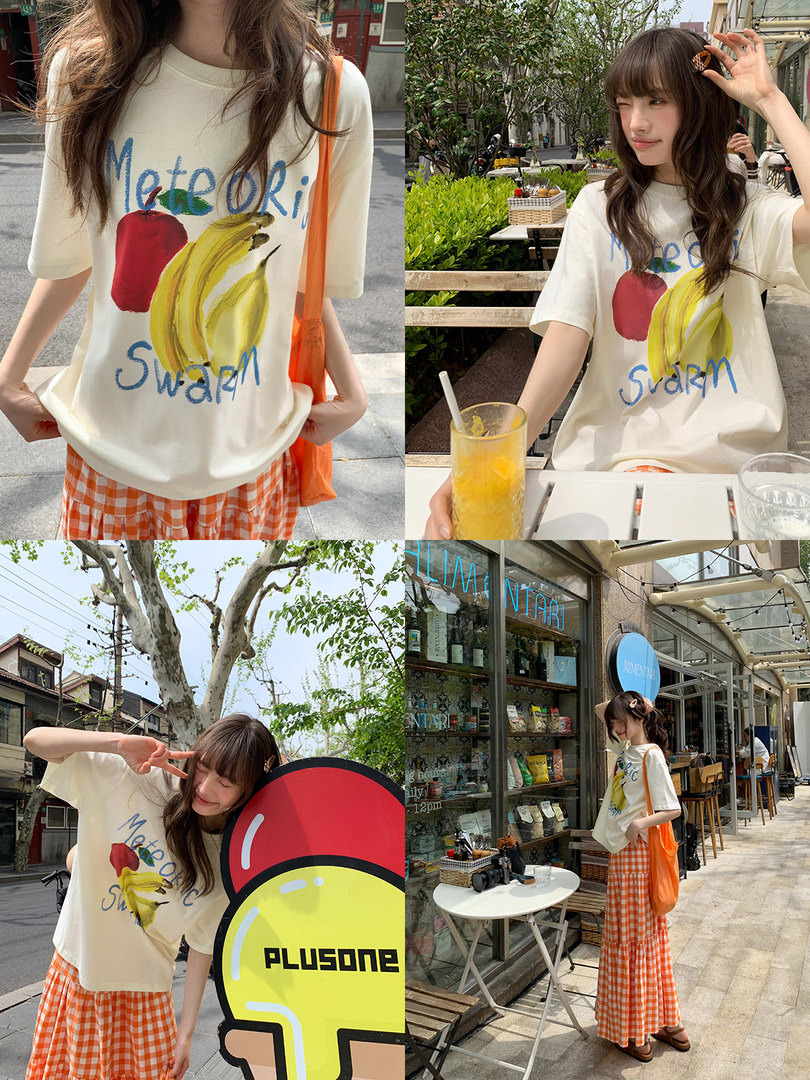 Model wearing a cream graphic T-shirt with an orange gingham skirt outdoors