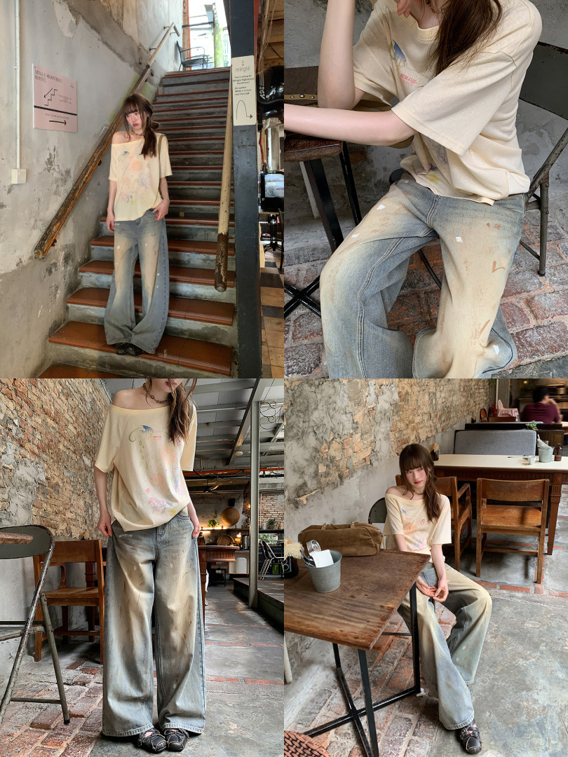 Model wearing an oversized cream graphic T-shirt and faded wide-leg jeans