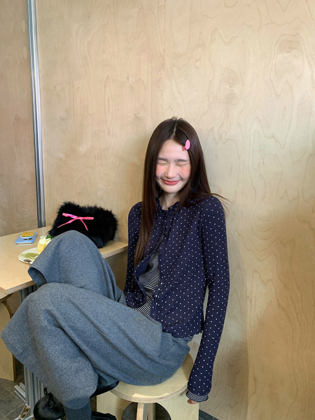 Woman wearing a navy polka dot cardigan and gray wide-leg pants