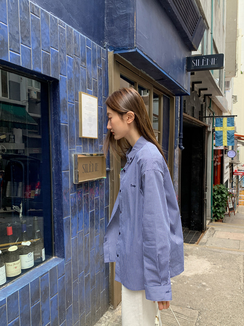 Model wearing an oversized blue checkered button-up shirt outdoors