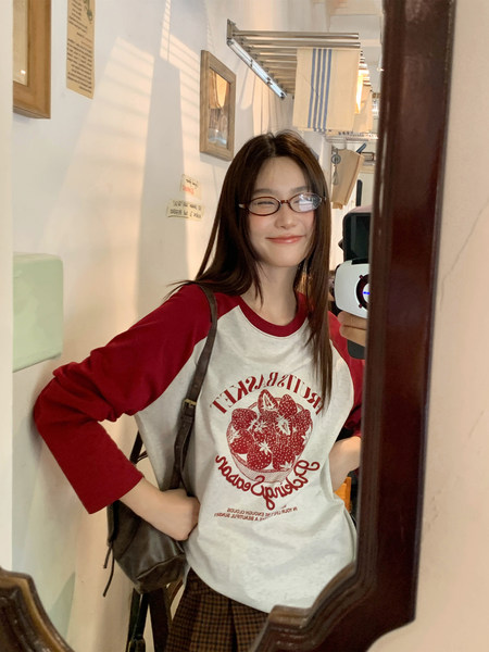 Woman wearing a red-and-white strawberry graphic raglan shirt in a mirror selfie