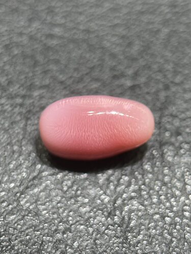 海螺珠呈椭圆形，粉色，表面布满细密的白色丝缕状火焰纹 3.2ct