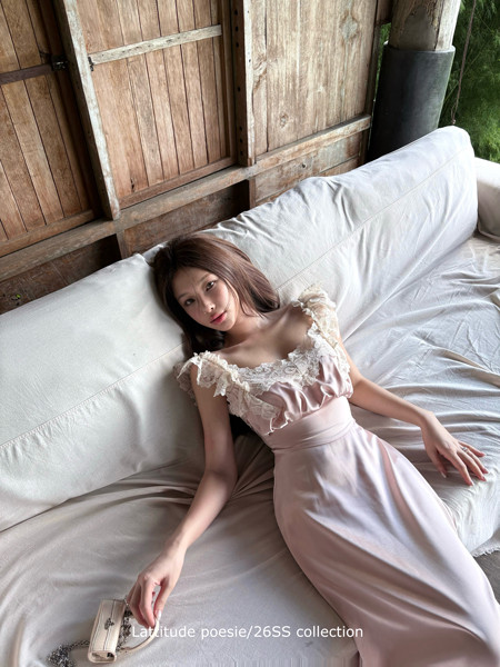 Woman wearing a light pink satin lace-trim dress on a sofa