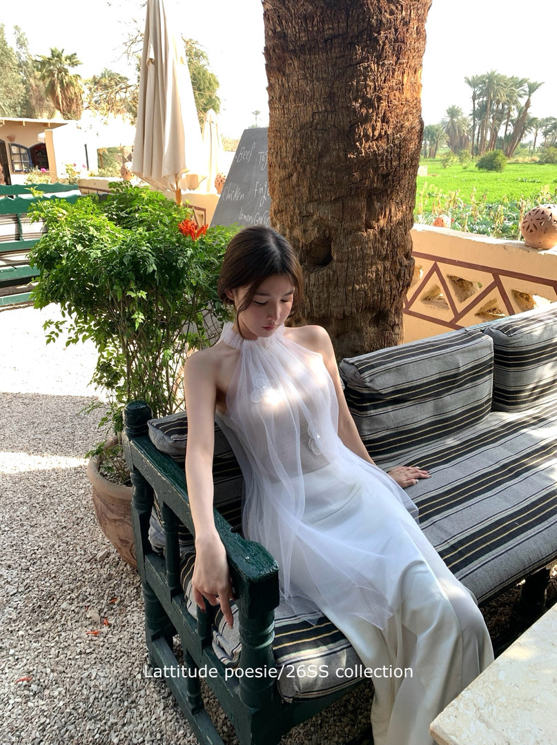 Woman wearing a white sheer halter dress outdoors