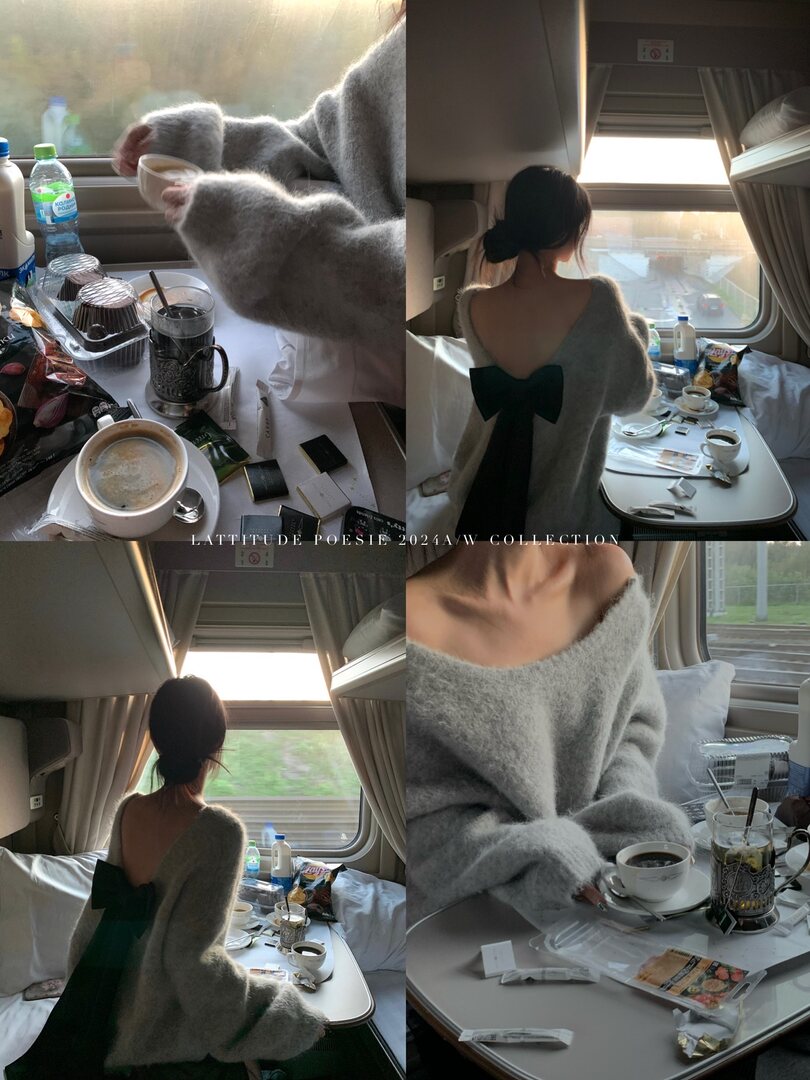 Gray fuzzy off-shoulder sweater dress with large back bow, worn on a model in a train cabin