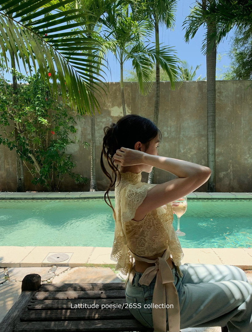 Woman wearing a beige lace sleeveless top by a pool