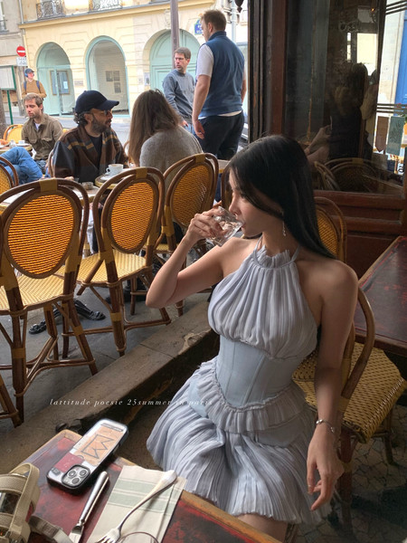 Light gray halter mini dress worn by a woman at a café