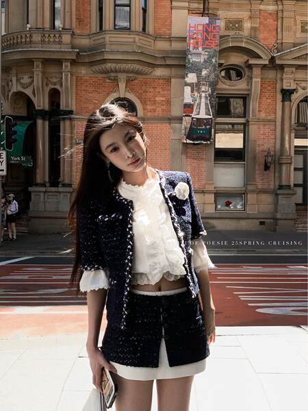 Model wearing a navy tweed jacket and skirt set with a white blouse outdoors