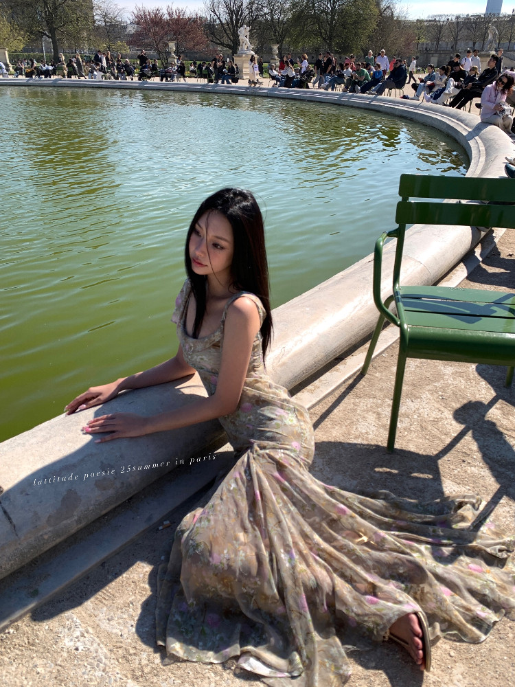 Woman wearing a flowing floral maxi dress outdoors by a fountain