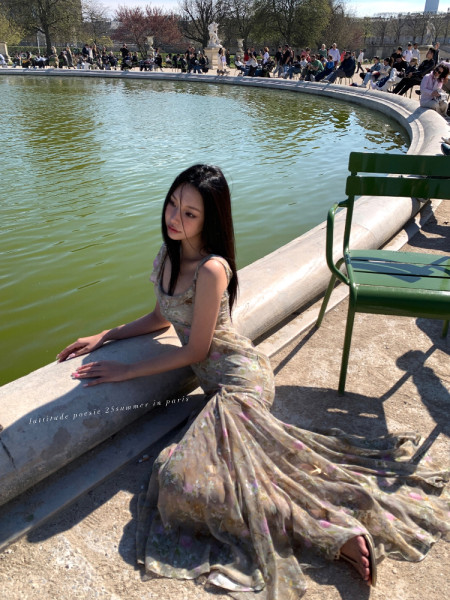 Woman wearing a flowing floral maxi dress outdoors by a fountain